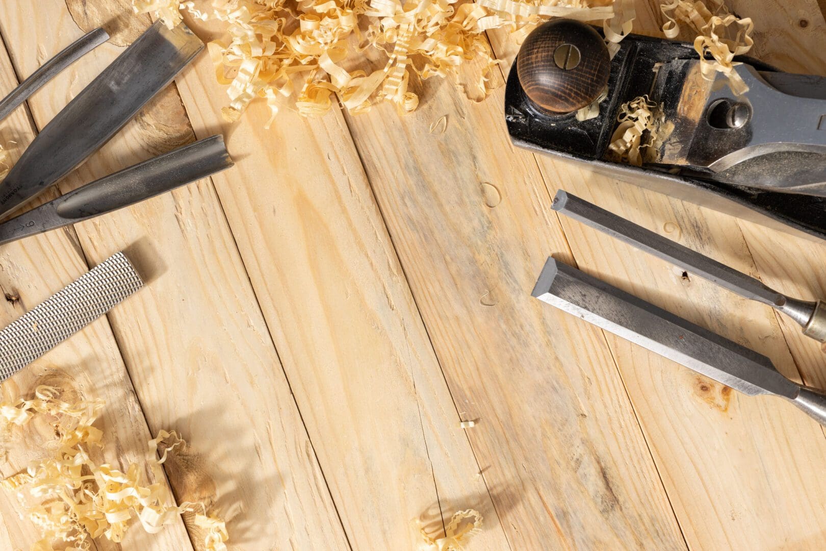 Woodworking tools and shavings arranged on a wooden surface.