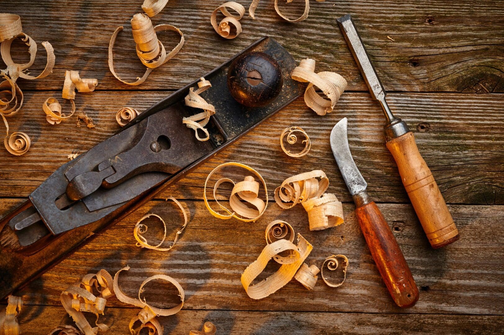 Woodworking tools and wood shavings on a rustic wooden surface.
