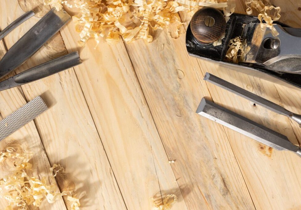 Woodworking tools and shavings arranged on a wooden surface.